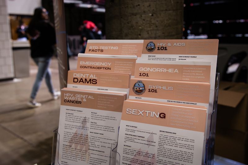 Orange-and-white pamphlets reading “STD testing and facts,” “Emergency contraception,” “Dental dams,” “HPV, genital warts, and cancer,” “HIV and AIDS 101,” “Gonorrhea 101,” “Syphilis 101,” and “sexting.”