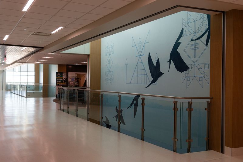 Hallway in a health center with a mural depicting tribal symbols and silhouettes of birds flying.