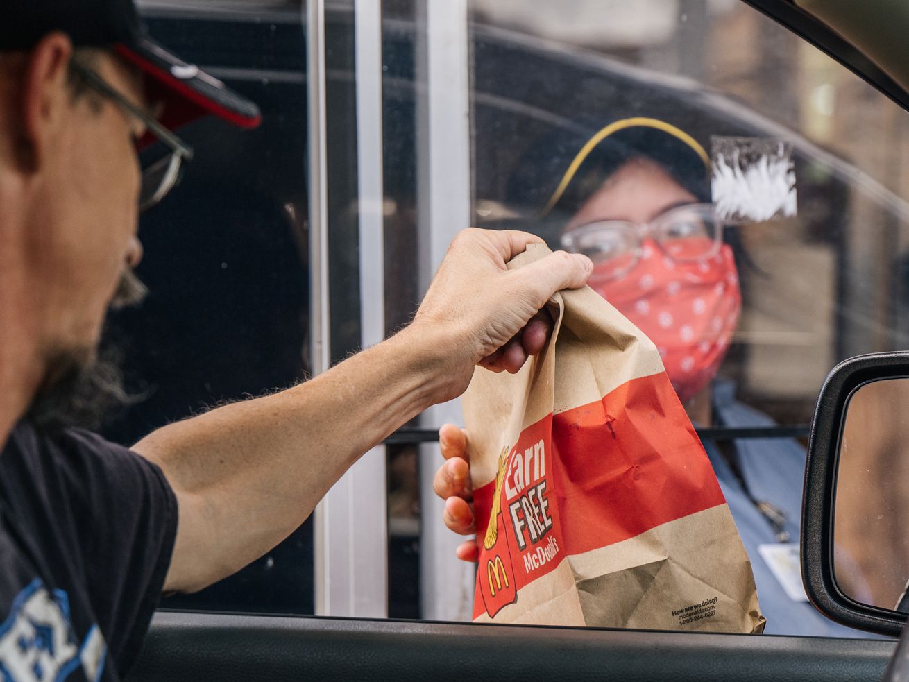 A McDonald’s worker hands a paper bag to a customer at a drive-through window in Houston, Texas.