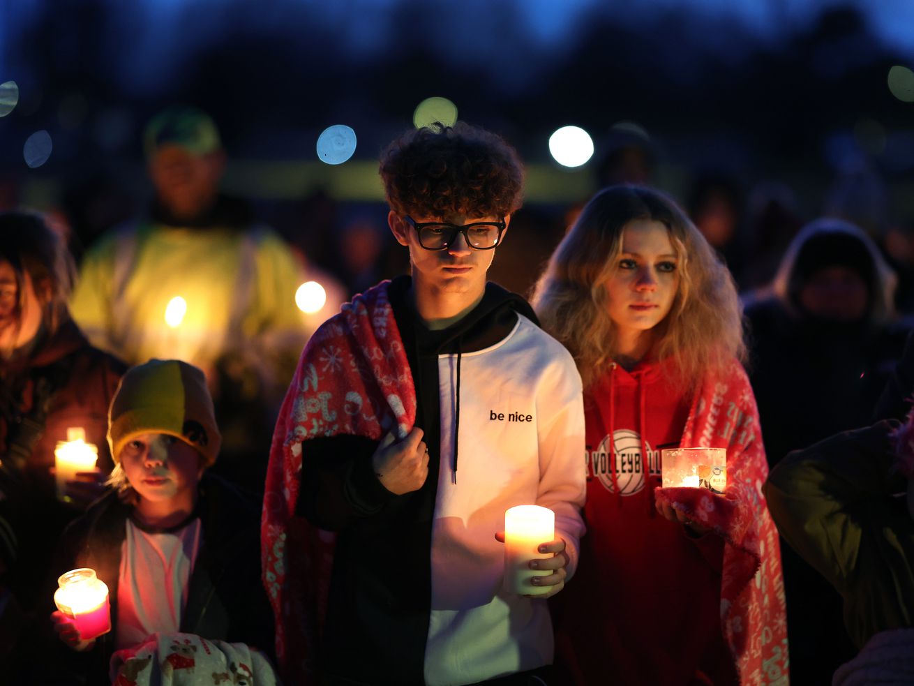 Young people holding candles at a vigil.