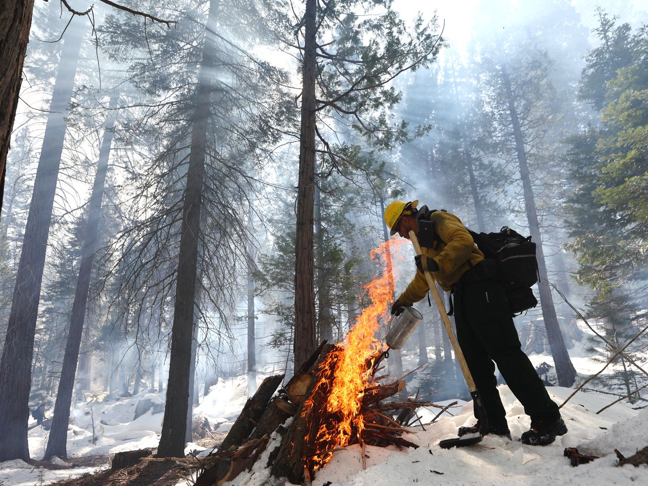 A firefighter burns a pile of wood in a snowy forest on February 19, 2023. 